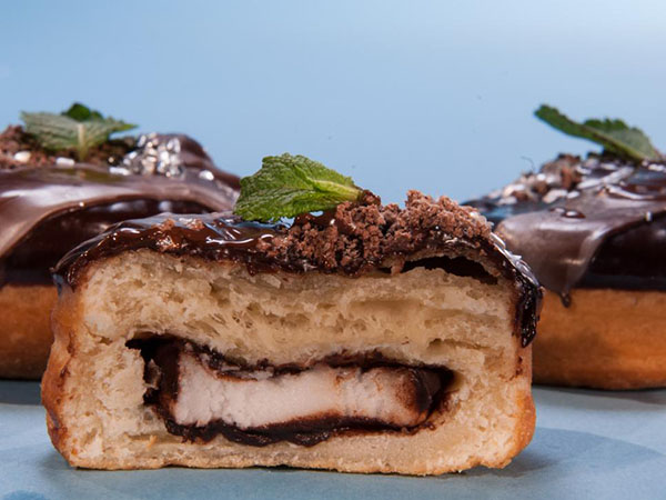 Warm Peppermint Pattie yeast doughnut topped with chocolate mirror glaze, chocolate dirt and fresh mint